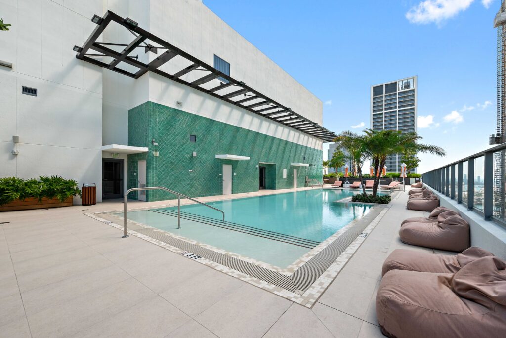 Real estate photography of a modern rooftop pool at a luxury Miami condo building with city skyline views — Skyview Real Estate Media