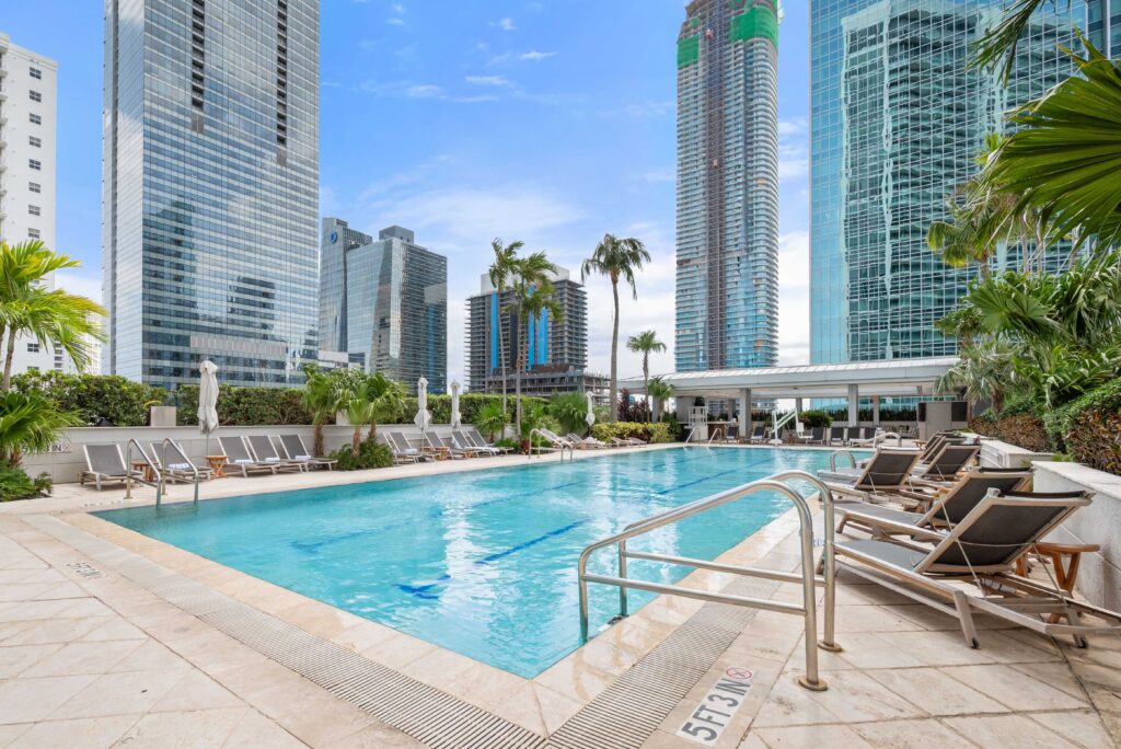 Vacation rental photography of a resort-style pool surrounded by Downtown Miami skyscrapers and palm trees in Brickell — Skyview Real Estate Media